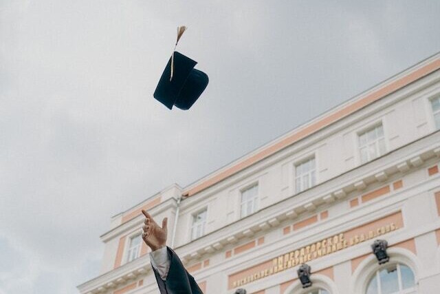 man throwing graduation cap in air