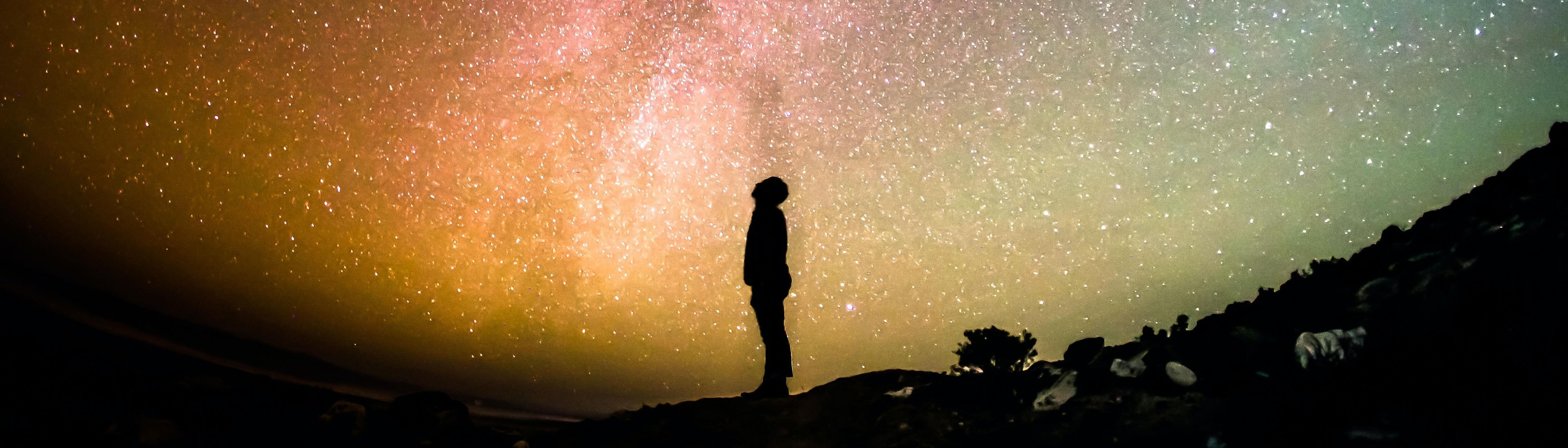 person looking up at the sky with a galaxy of stars